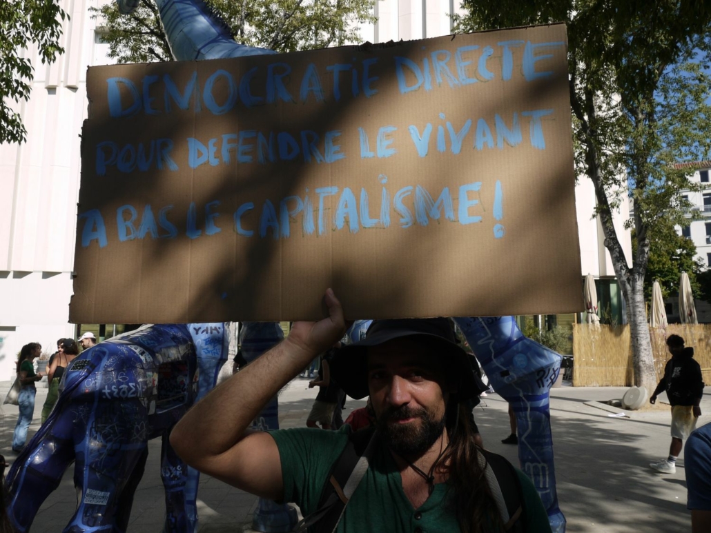 Manifestation du 10/09/25 à Marseille. Un manifestant tient une pancarte "Démocratie directe : pour défendre le vivant, à bas le capitalisme" © Gaëlle Cloarec