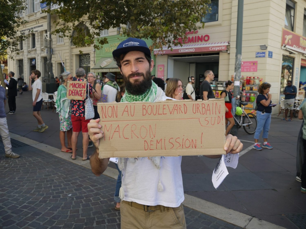 Manifestation du 18/09/25 à Marseille. Un manifestant tient une pancarte "Non au Boulevard Urbain Sud / Macron démission" © Gaëlle Cloarec